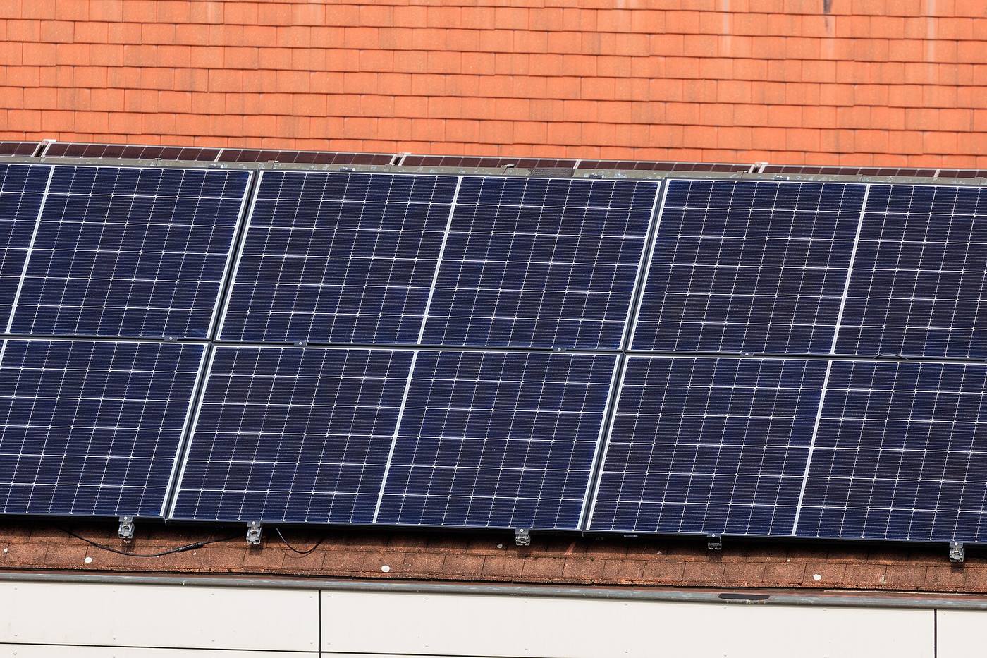 Twee rijen zonnepanelen op een oranje pannendak, met de montagehaken zichtbaar aan de onderrand
