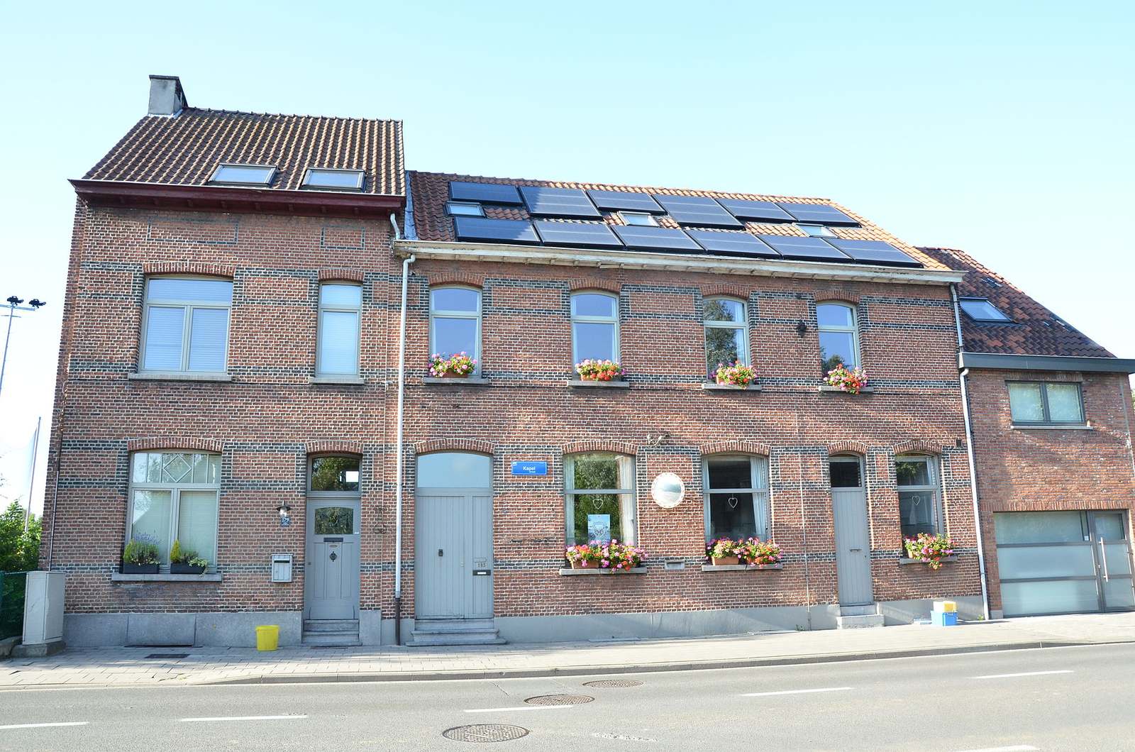 Gerenoveerde rij arbeiderswoningen in rode baksteen met zonnepanelen en dakvensters op het pannendak